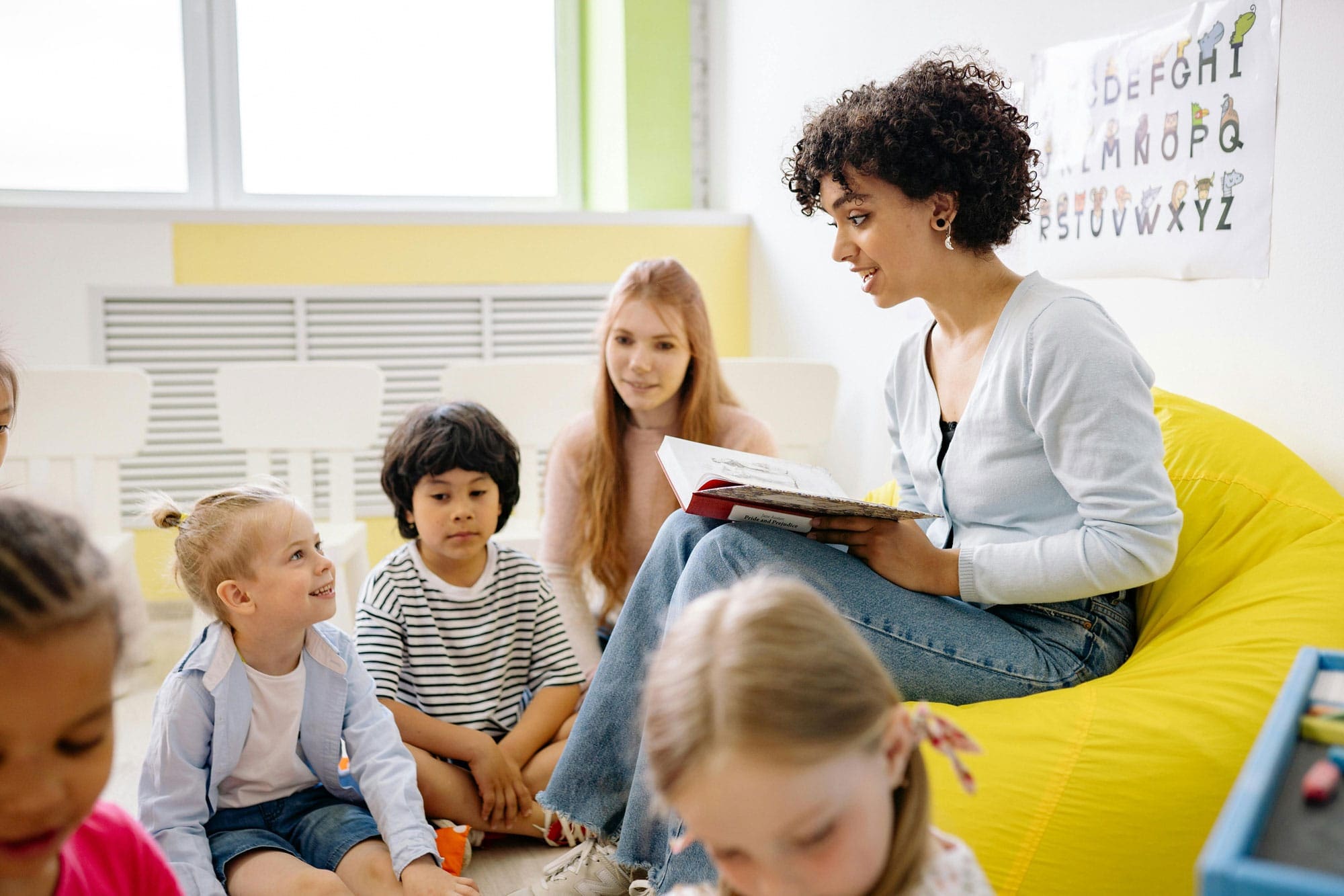 A teacher reading aloud to young children sitting in a circle in a classroom