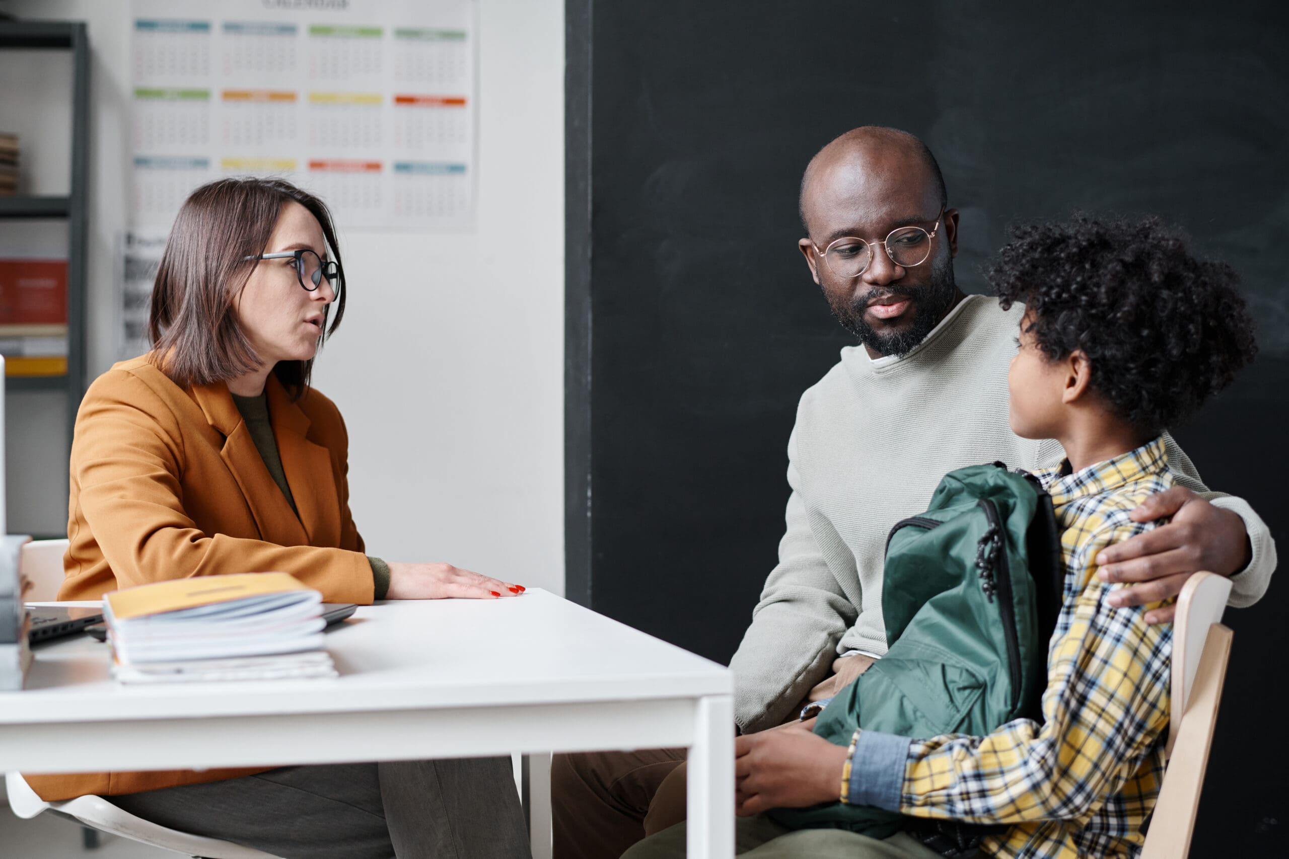 A parent and child meeting with a school administrator across a table during a school visit